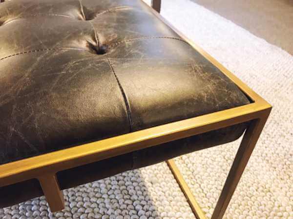 Gold frame on a black leather ottoman|by Design Des Moines